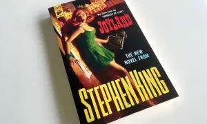 Bokomslaget till Stephen Kings "Joyland" med en skräckslagen kvinna i en grön klänning. En av många filmer med Stephen King som väntar på att bli sedd.
