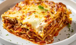 En saftig bit lasagne med lager av köttfärssås, béchamelsås och pasta, toppad med smält ost. Perfekt för ett gott lasagne recept.