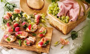 En härlig picknick med bruschetta, jordgubbar, vindruvor i korg och en stråhatt. Perfekt picknick mat för en solig dag.