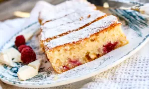 Skivad vit kladdkaka med hallon och vit choklad, pudrad med florsocker. En härlig dessert som smälter i munnen.