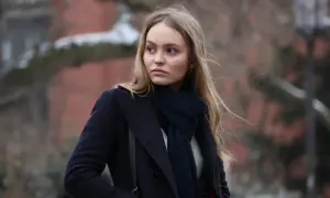 Lily-Rose Depp i en mörkblå kappa och halsduk, påminner om hennes roller i filmer.
