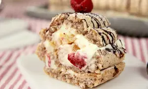 En läcker budapestbakelse med vispgrädde, frukt och chokladdrizzle, toppad med ett hallon.