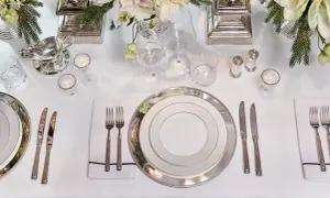 Elegant dukning med silverbestick på samma sida. Vita blommor och granris ger en festlig känsla.