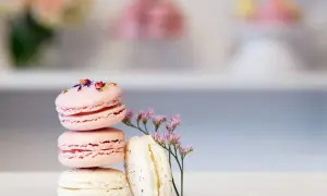 En stapel rosa och vita macarons, dekorerade med blommor. Perfekt för ett macarons recept.
