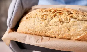 Nygräddat potatisbröd, gyllene och krispigt, tas ur ugnen. Perfekt att baka med potatis för en saftig och god limpa.