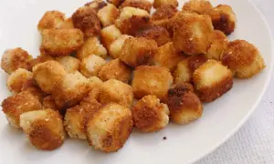 Krispiga, gyllene bitar av friterad tofu på en vit tallrik. Perfekt för ett snabbt och gott tofu recept.