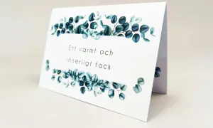 Ett tackkort efter begravning med texten "Ett varmt och innerligt tack" och dekorerat med eukalyptusblad.
