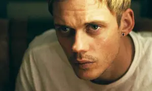 Bill Skarsgård med blont hår och en liten örhänge blickar intensivt mot betraktaren.