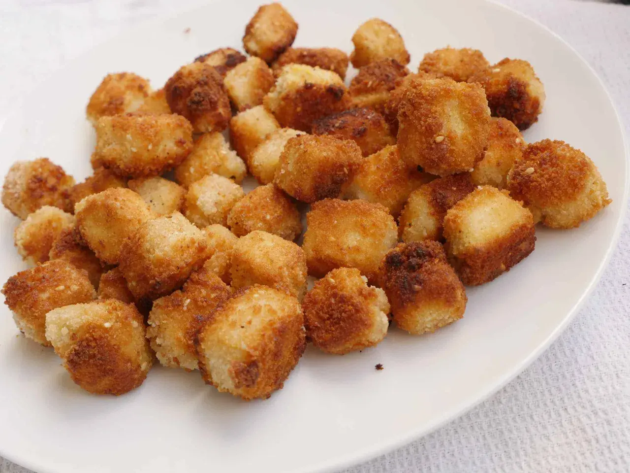 Krispiga, gyllene bitar av friterad tofu på en vit tallrik. Perfekt för ett snabbt och gott tofu recept.