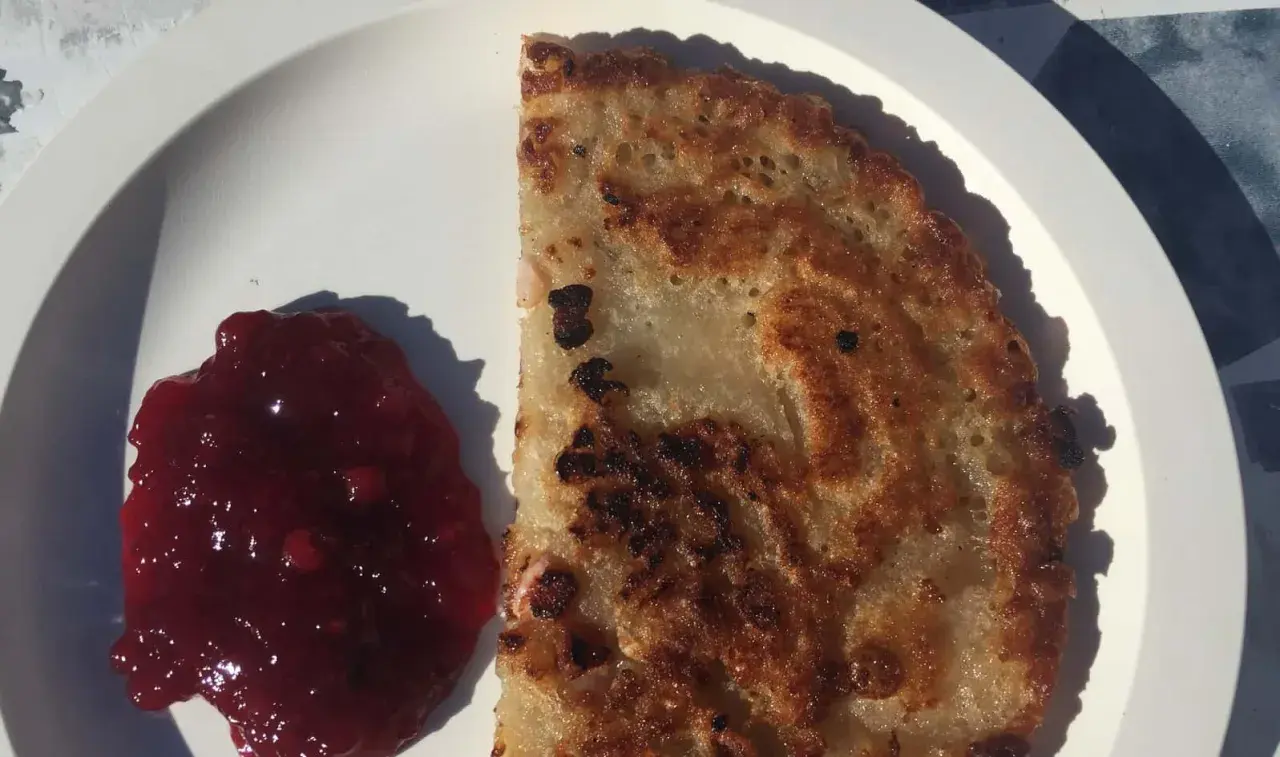 En gyllene kolbulle med lingonsylt på en vit tallrik. Perfekt för ett enkelt kolbulle recept.