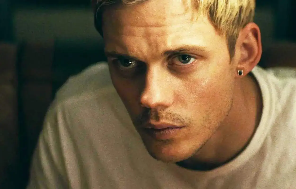 Bill Skarsgård med blont hår och en liten örhänge blickar intensivt mot betraktaren.