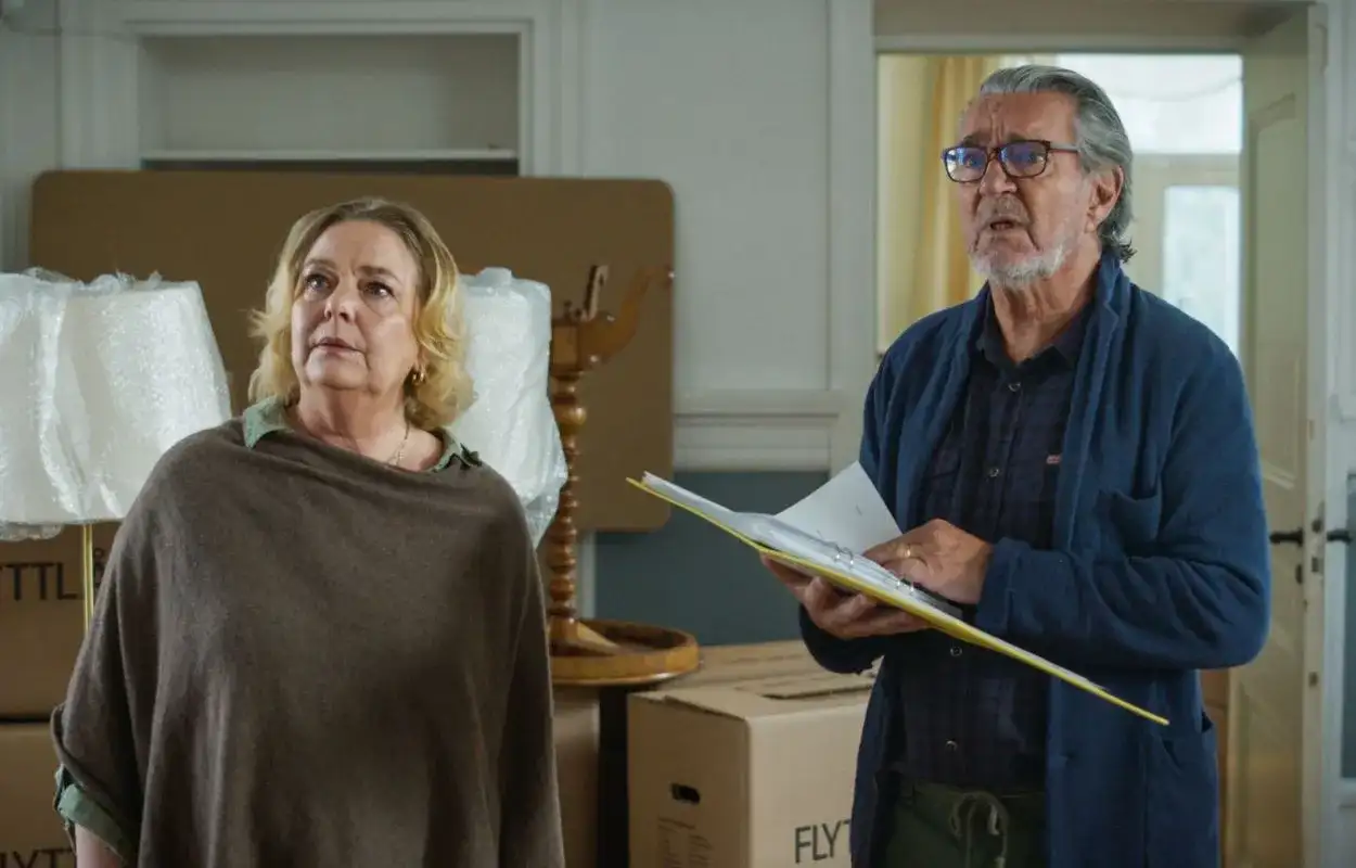 Två äldre personer, mitt i en flytt, verkar diskutera något viktigt. Kanske är det en scen från grannfejden film.