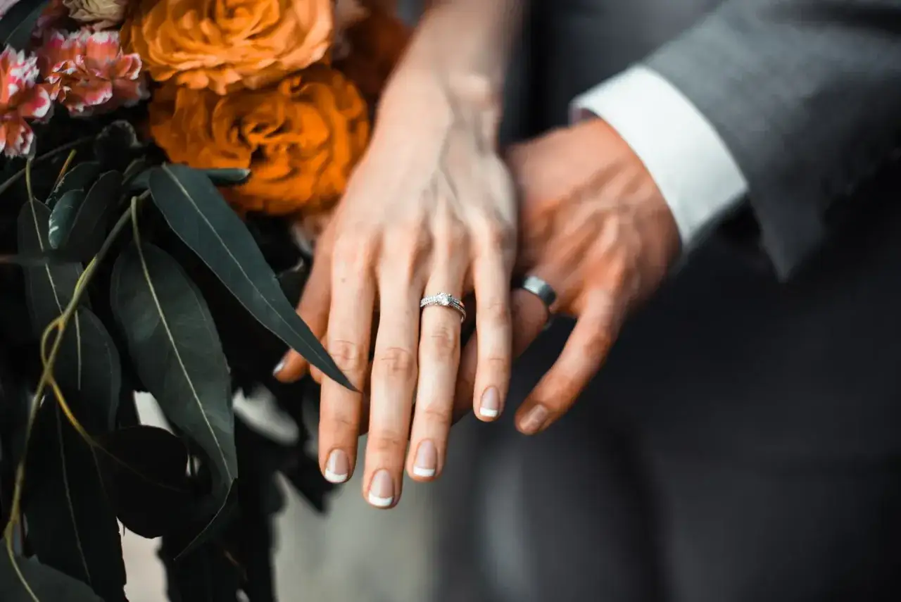 Här visas händerna på ett brudpar. Vigselringen bärs på vänster ringfinger, vilket är traditionen i Sverige.