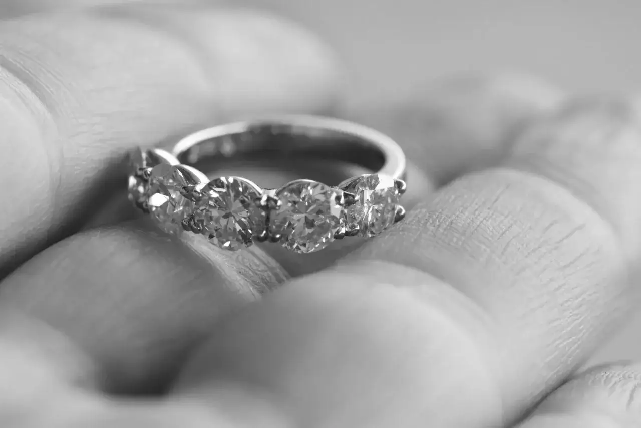 En hand håller en diamantring, en symbol för hur friar man.
