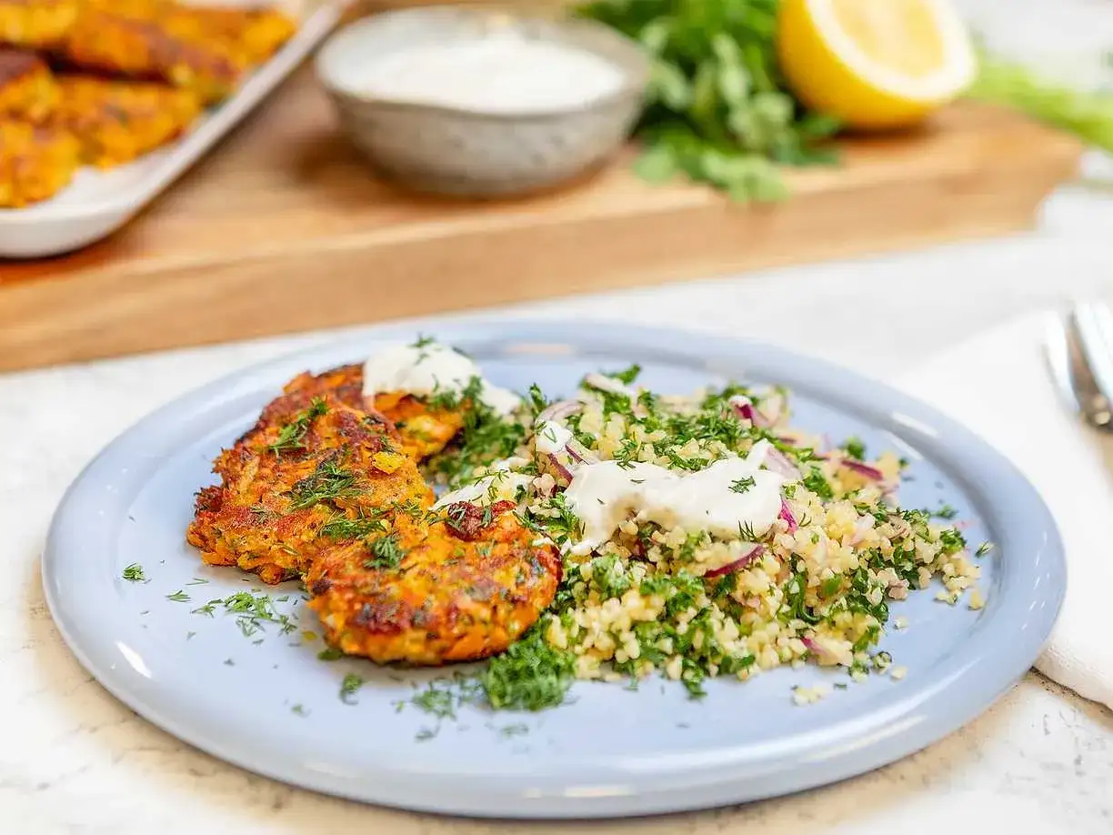 Halloumi och morotsbiffar serveras med en frisk bulgursallad och en klick kr&auml;mig s&aring;s. Garnerat med f&auml;rska &ouml;rter.