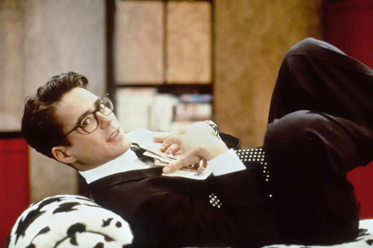Robert Downey Jr. i en scen från en av hans filmer, med glasögon och en kostym, liggandes bekvämt.