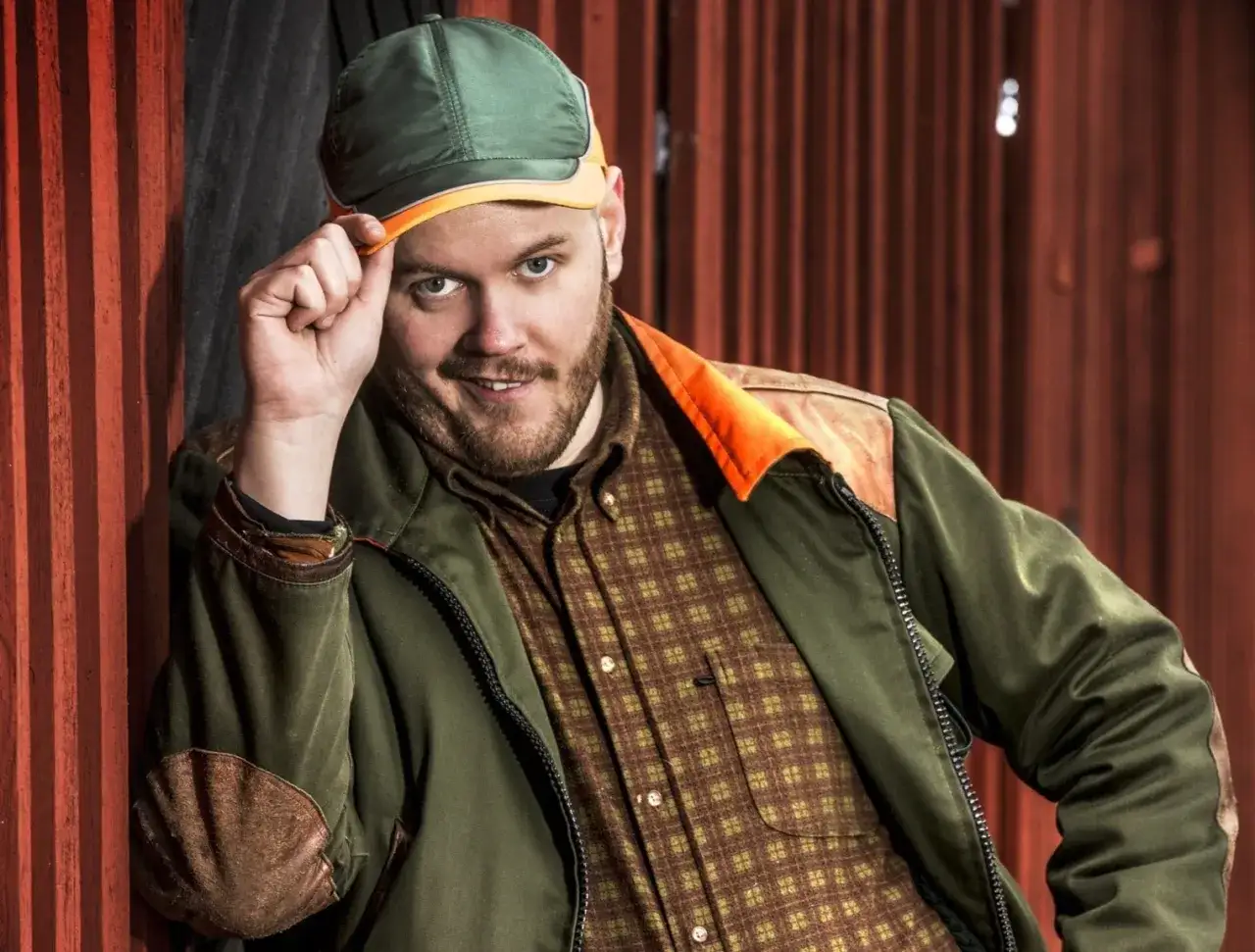 En leende man med sk&auml;gg och keps, kl&auml;dd i en rutig skjorta och jacka. Kanske en scen fr&aring;n leif och billy film?