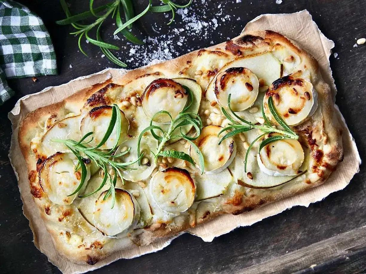 En läcker pinsa med chevre, tunna potatisskivor och rosmarin, toppad med pinjenötter.