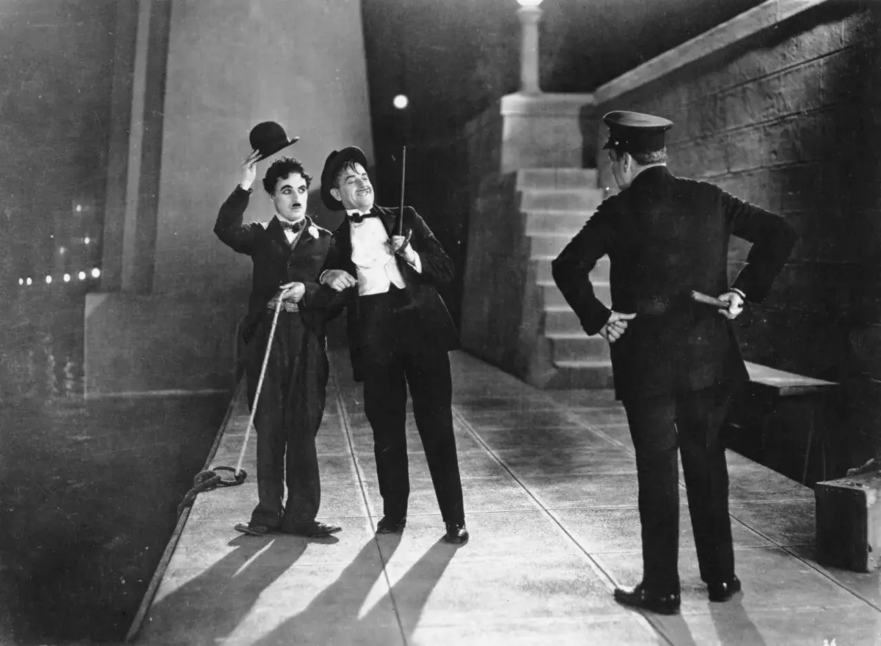 Charlie Chaplin och en v&auml;n i en klassisk scen fr&aring;n hans filmer, m&ouml;ter en polis.