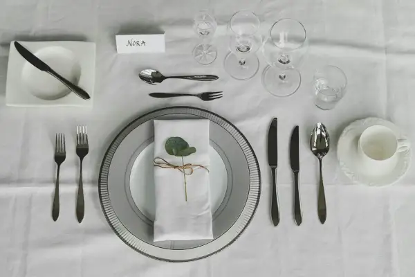 Vackert dukat bord med en namnskylt för Nora. En elegant uppsättning av kniv och gaffel, glas och porslin väntar.